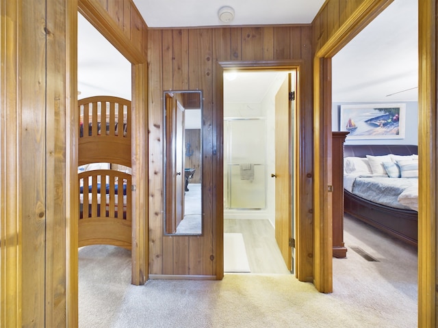 hall featuring light carpet and wood walls