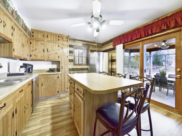 kitchen featuring appliances with stainless steel finishes, light wood-type flooring, a center island, ceiling fan, and sink