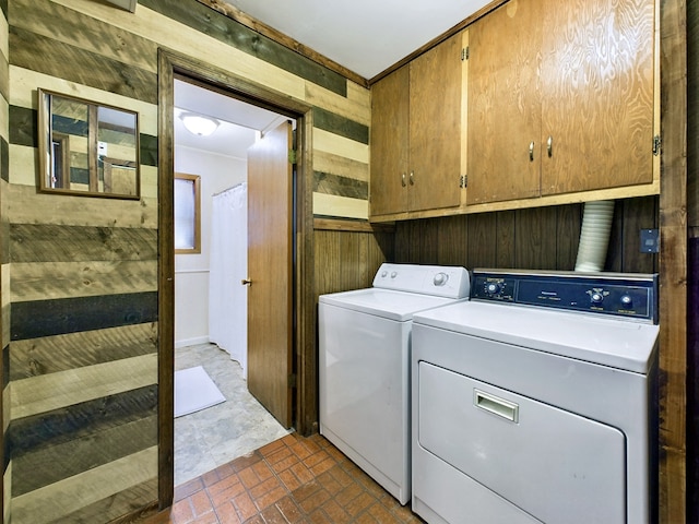 washroom featuring cabinets, wood walls, and independent washer and dryer