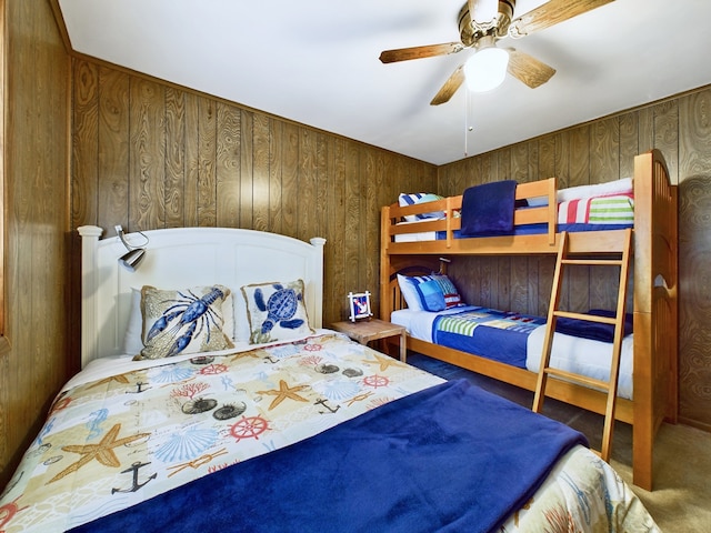 carpeted bedroom with wood walls and ceiling fan