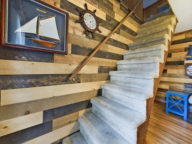 staircase with wood-type flooring and wooden walls