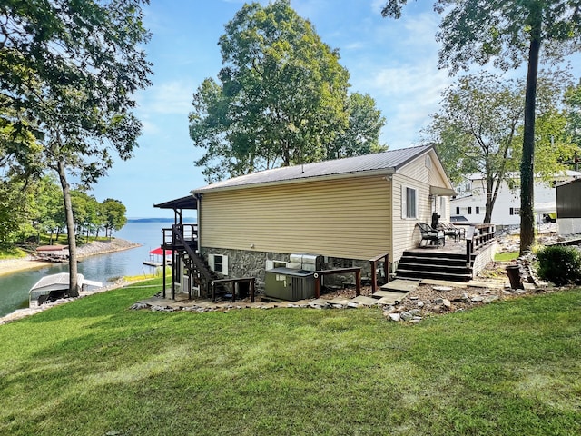 rear view of house with a deck with water view, central air condition unit, and a yard