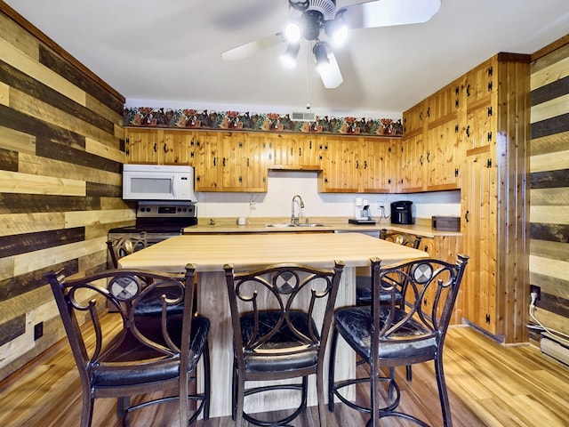 kitchen with light wood-type flooring, wooden walls, and stainless steel electric range oven