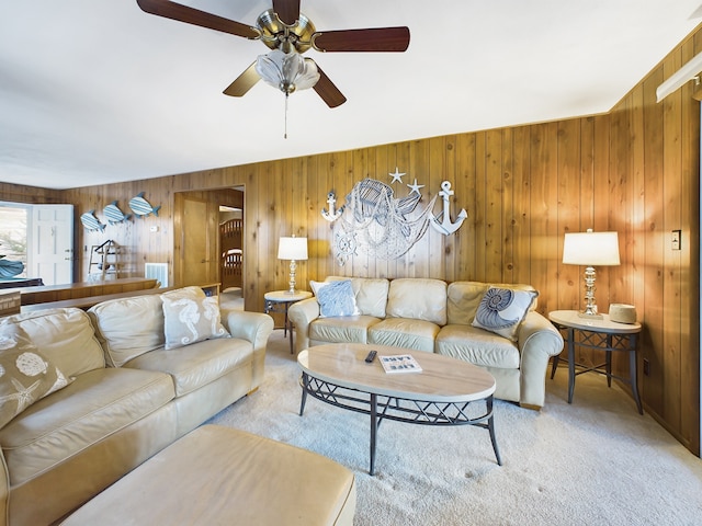 living room with wooden walls, ceiling fan, and carpet flooring