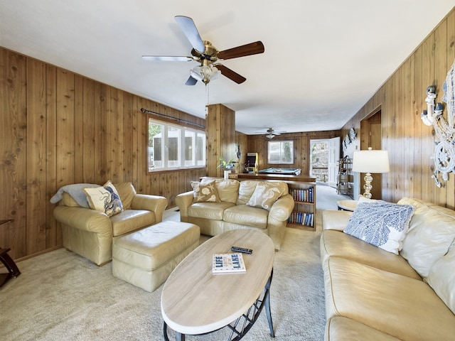 living room with wood walls, light carpet, and ceiling fan