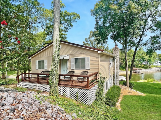 rear view of property featuring a lawn and a deck with water view