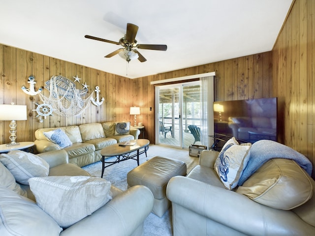 carpeted living room featuring wooden walls and ceiling fan