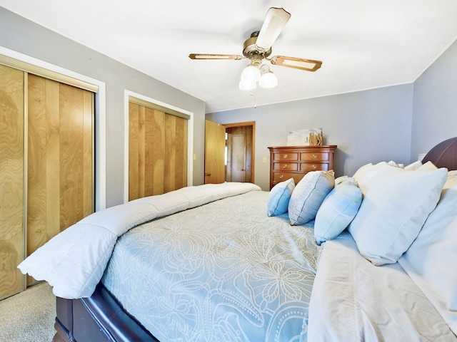 carpeted bedroom featuring ceiling fan and multiple closets