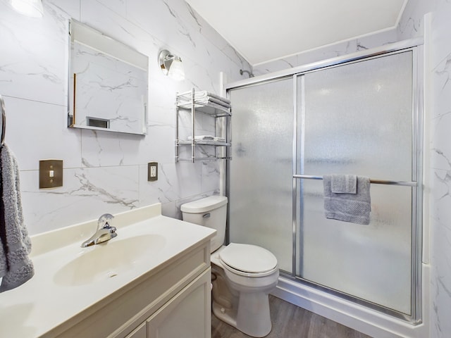 bathroom with tile walls, a shower with shower door, vanity, hardwood / wood-style flooring, and toilet