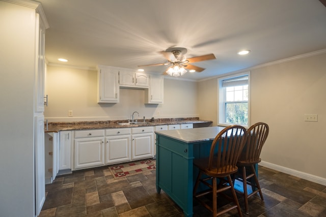 kitchen featuring white cabinets, ceiling fan, crown molding, and sink