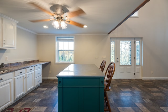 kitchen featuring white cabinetry, ceiling fan, a kitchen island, and crown molding