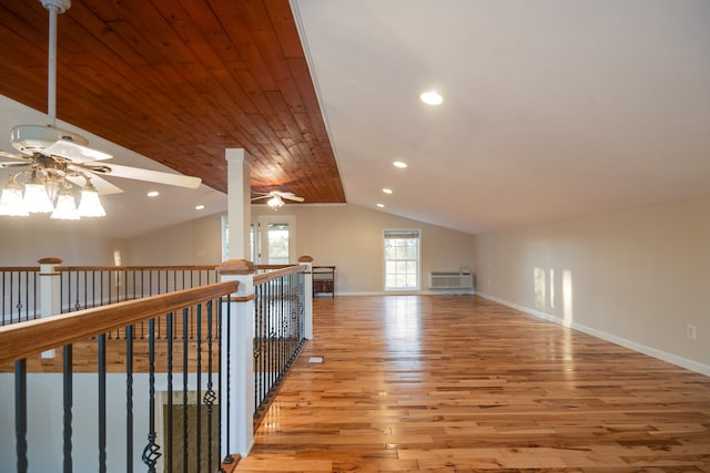 corridor featuring light wood-type flooring, vaulted ceiling, a wall unit AC, and wooden ceiling