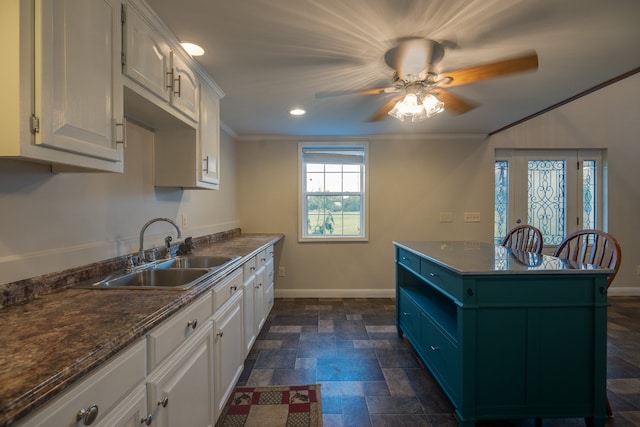 kitchen with ceiling fan, white cabinets, blue cabinets, sink, and crown molding