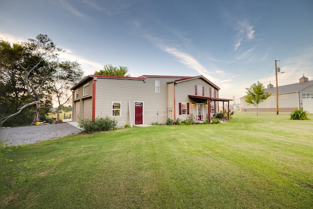 rear view of house featuring a yard and a garage