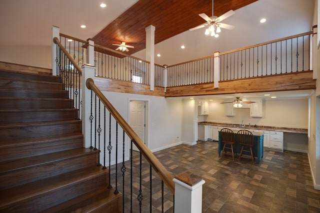 stairway with ceiling fan, high vaulted ceiling, and wooden ceiling