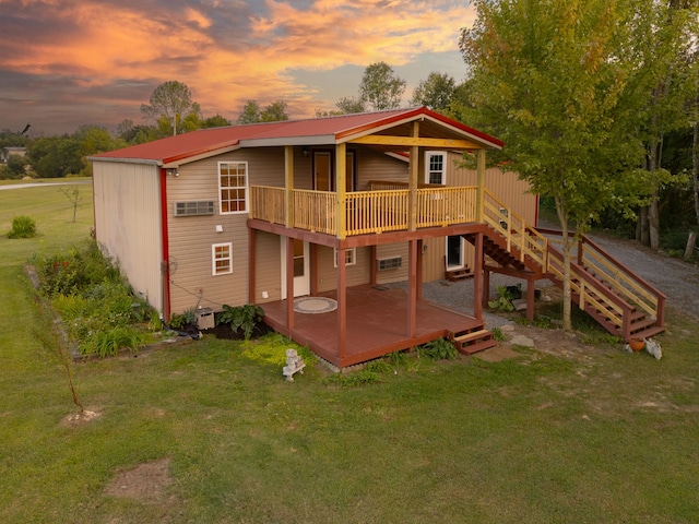 back house at dusk featuring a lawn and a deck