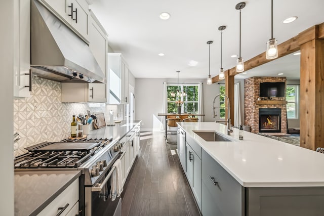 kitchen featuring pendant lighting, dark hardwood / wood-style floors, a kitchen island with sink, sink, and appliances with stainless steel finishes