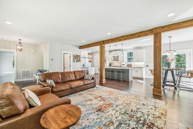 living room featuring a notable chandelier and dark wood-type flooring