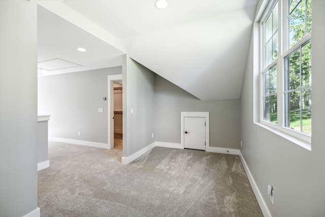 additional living space with vaulted ceiling and light carpet