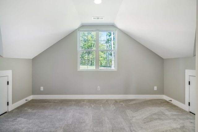 bonus room with vaulted ceiling and light colored carpet