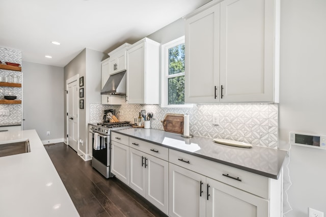 kitchen featuring gas range, white cabinetry, range hood, dark hardwood / wood-style flooring, and decorative backsplash