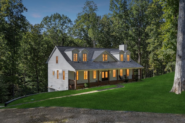 cape cod home with a front yard and a porch