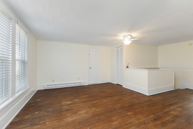 spare room with dark wood-type flooring and a baseboard heating unit