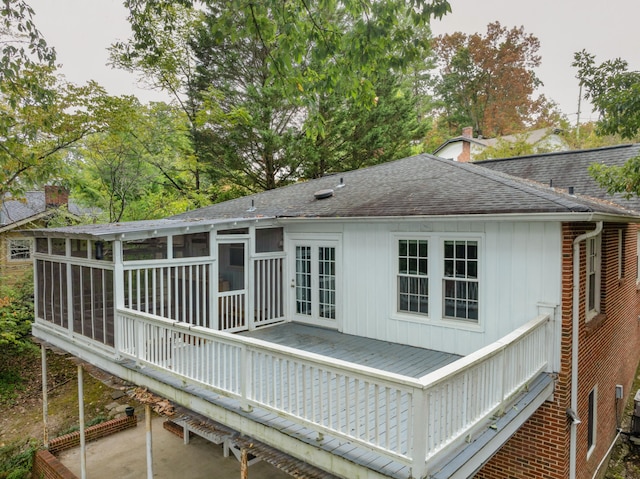 rear view of house featuring a wooden deck, a sunroom, and a patio area