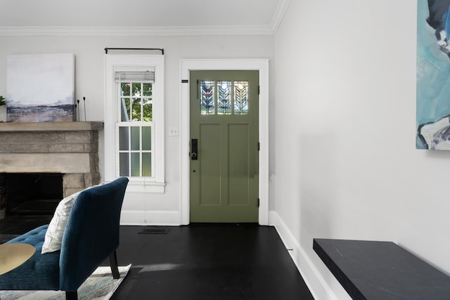 foyer entrance with crown molding and a stone fireplace