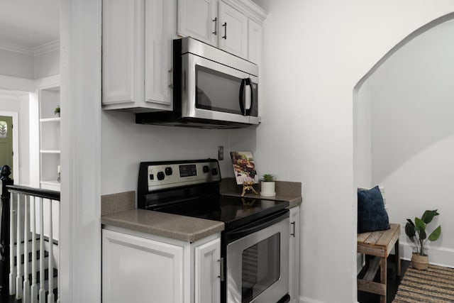 kitchen with appliances with stainless steel finishes, white cabinets, and ornamental molding