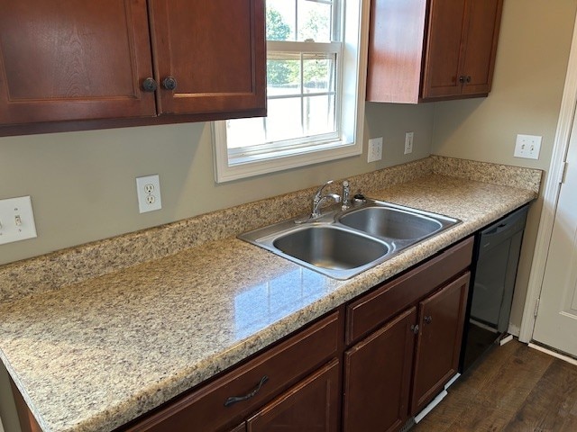 kitchen with light stone countertops, black dishwasher, dark hardwood / wood-style floors, and sink