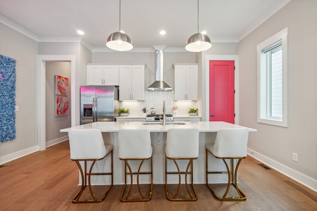 kitchen with wall chimney range hood, stainless steel refrigerator with ice dispenser, light hardwood / wood-style floors, and white cabinets