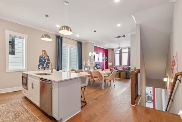 kitchen featuring sink, appliances with stainless steel finishes, decorative light fixtures, a kitchen island with sink, and white cabinets