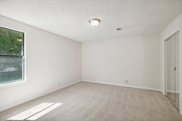 unfurnished bedroom with a textured ceiling, light carpet, and a closet