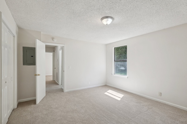 unfurnished bedroom with a textured ceiling, electric panel, light carpet, and a closet