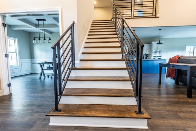 staircase with coffered ceiling, beamed ceiling, and hardwood / wood-style flooring