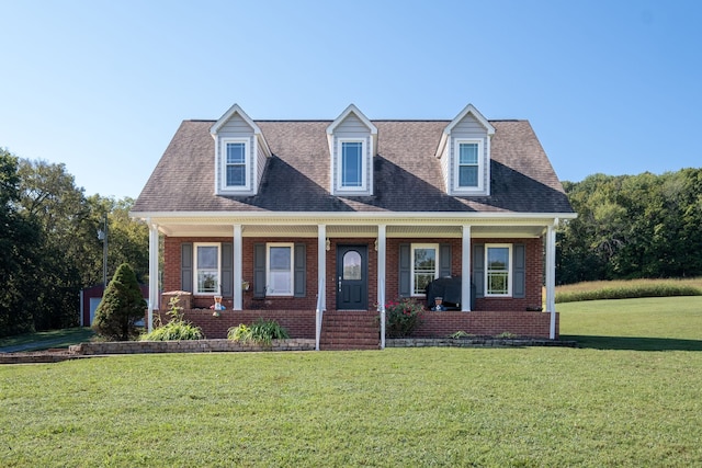 new england style home featuring covered porch and a front yard