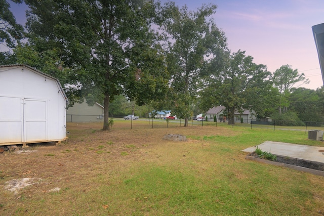 yard at dusk with cooling unit and a storage unit