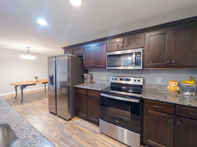 kitchen featuring stainless steel appliances, light stone counters, light hardwood / wood-style floors, and dark brown cabinetry