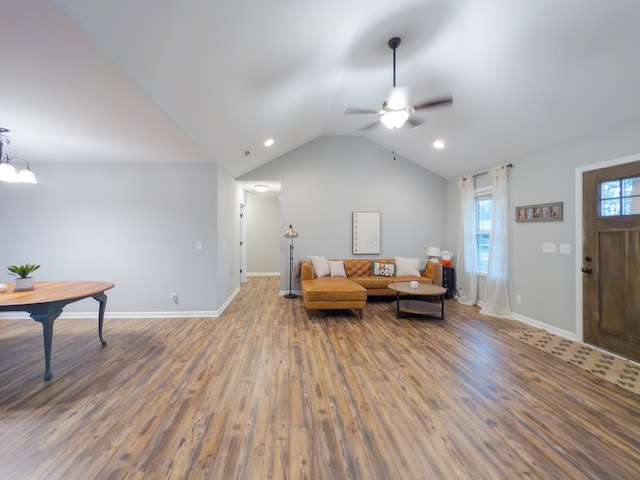 living area with ceiling fan with notable chandelier, vaulted ceiling, and hardwood / wood-style floors