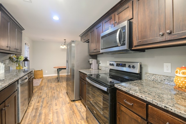 kitchen featuring dark brown cabinetry, light stone countertops, light hardwood / wood-style flooring, and stainless steel appliances