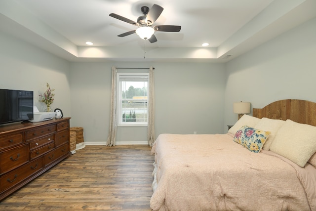 bedroom featuring ceiling fan, a raised ceiling, and dark wood-type flooring