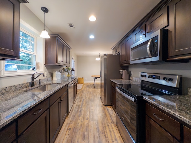 kitchen featuring light hardwood / wood-style floors, sink, hanging light fixtures, appliances with stainless steel finishes, and dark brown cabinetry