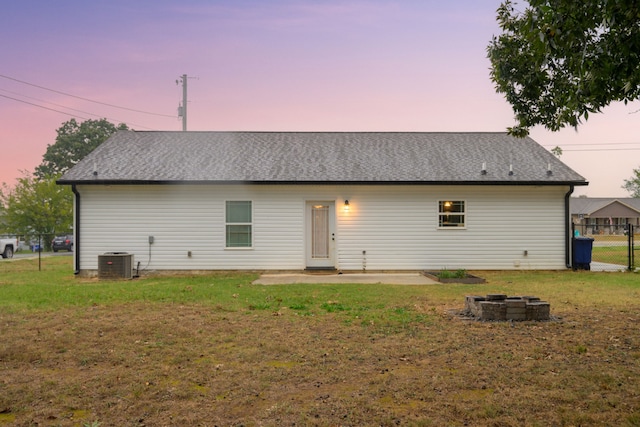 back house at dusk featuring a lawn, a patio, and cooling unit