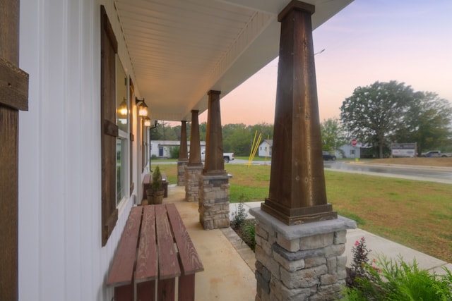 patio terrace at dusk with a porch and a lawn