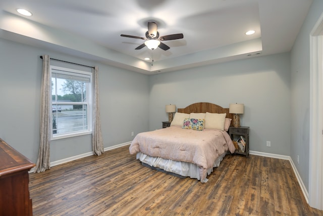 bedroom featuring ceiling fan, a raised ceiling, and dark hardwood / wood-style floors