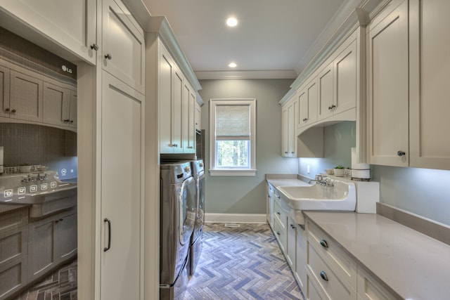 laundry area featuring light parquet flooring, crown molding, cabinets, sink, and washer and dryer