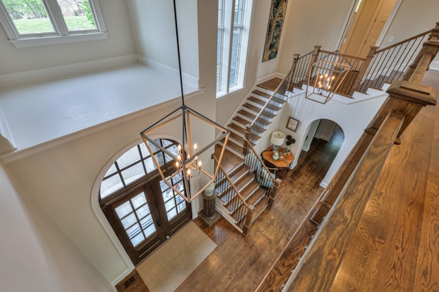 staircase with french doors, wood-type flooring, a chandelier, and a healthy amount of sunlight