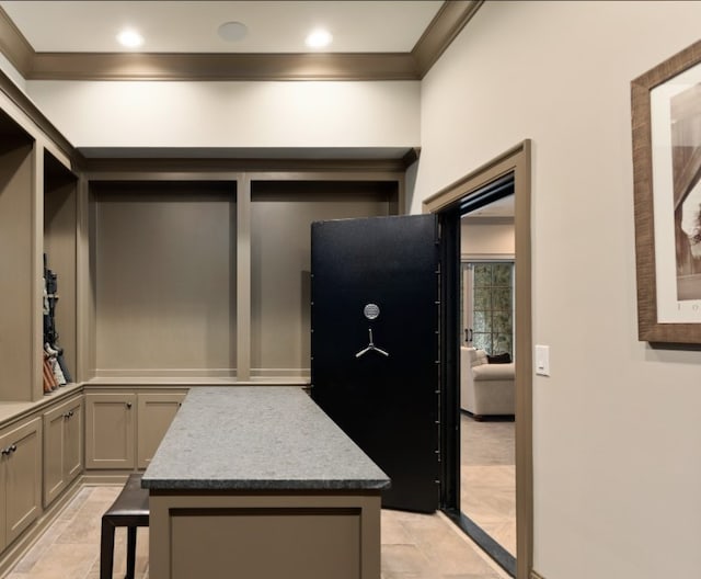 interior space featuring gray cabinetry, a breakfast bar area, ornamental molding, and a center island