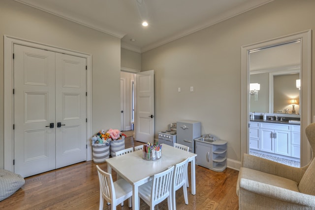 dining room with ornamental molding, hardwood / wood-style flooring, and sink